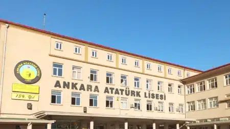 Ankara Atatürk Lisesi’nin üç katlı, krem renkli ana binası; cephede “ANKARA ATATÜRK LİSESİ” harfleri, solda 1886 tarihli okul amblemi ve “139. Yıl” levhası, üstte mavi gökyüzü