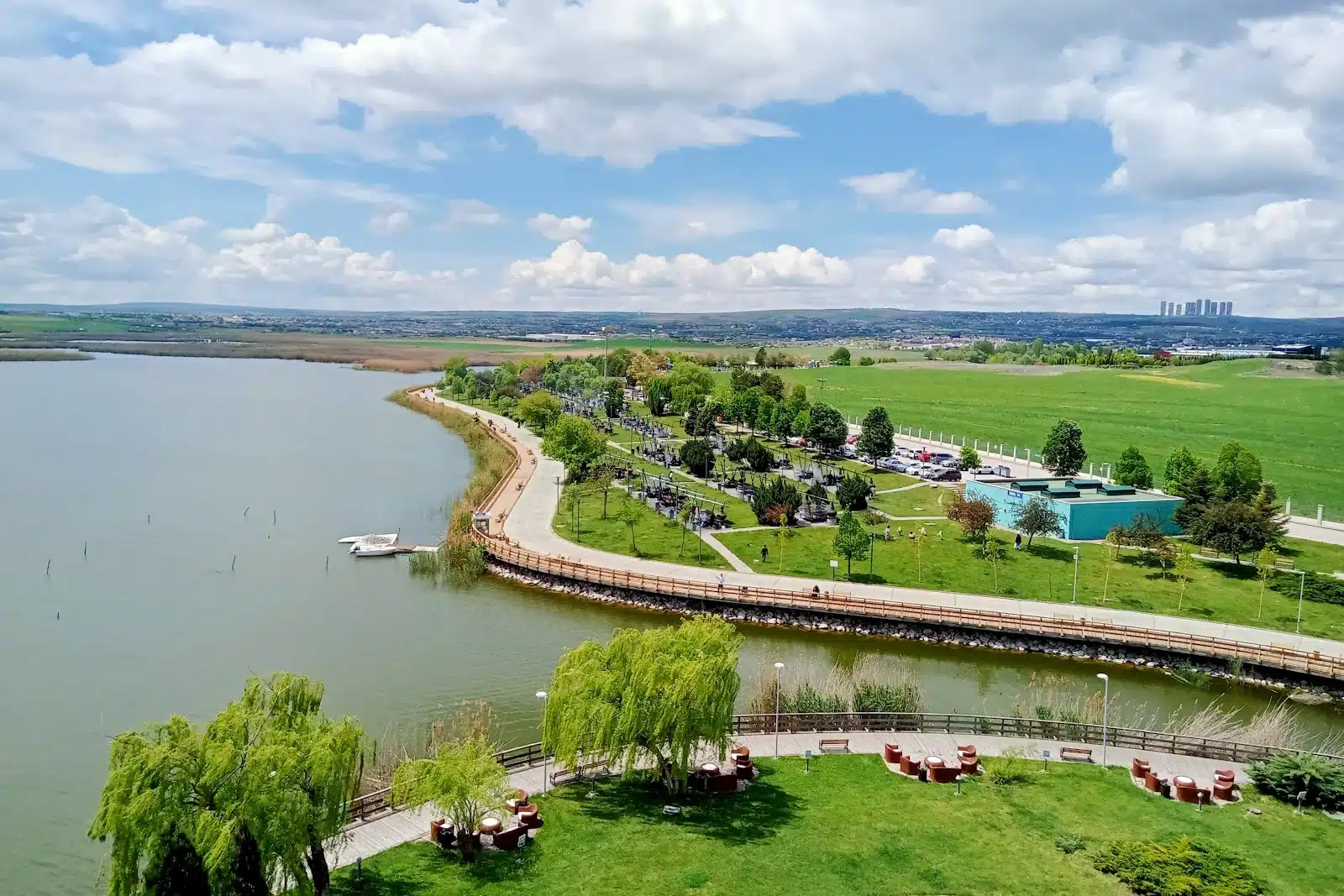 Gölbaşı Mogan Parkı’na seyir kulesinden bakış: Mogan Gölü, kıyı boyunca ahşap yürüyüş yolu, ağaçlar arasında kamelyalı piknik ve mangal alanı