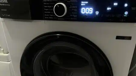 Beyaz Vestel çamaşır makinesinin önden görünümü: siyah kontrol panelinde Vestel logosu, program seçme düğmesi ve mavi ışıklı dijital ekranda 0:09 süre, 30 °C ve 800 devir göstergeleri; altta siyah çerçeveli yuvarlak kapak ve “Inverter” etiketi
